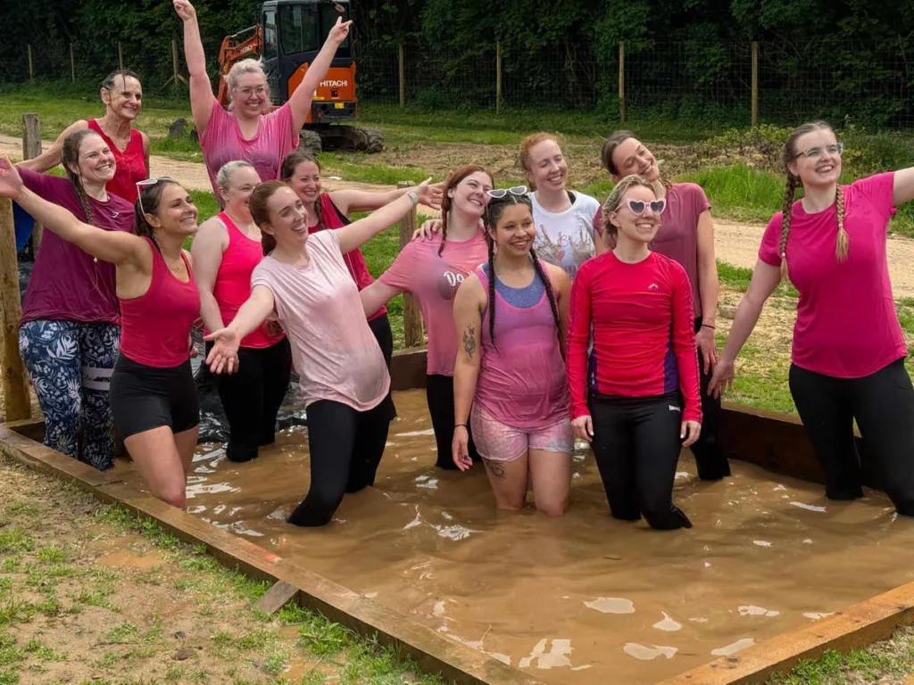 A group enjoying the muddy water obstacle on the assault course at Escot Park, Devon.