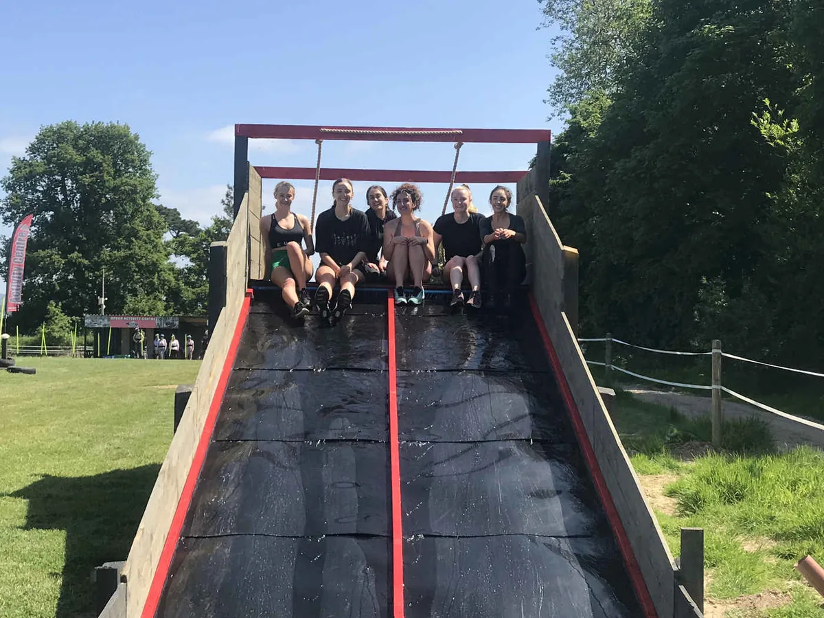 A group at the top of an outdoor slide on the assault course at Escot Park, Devon.
